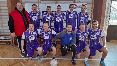 Emberek játszanak beltéri futball szimulátoron, nagy kivetítővel