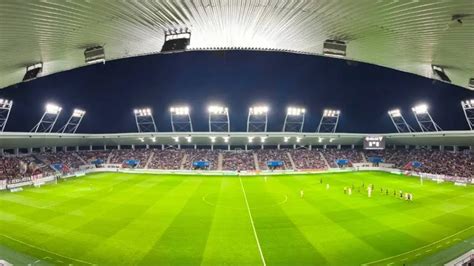 Labdarúgó stadion telt házas lelátókkal, esti megvilágításban