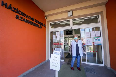 Zsúfolt bevásárlóközpont bejárata, ahol maszkot viselő vásárlók várakoznak