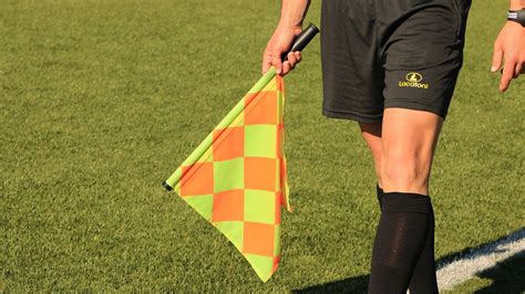 Labdarúgó játékvezető asszisztens zászlóval a pályán