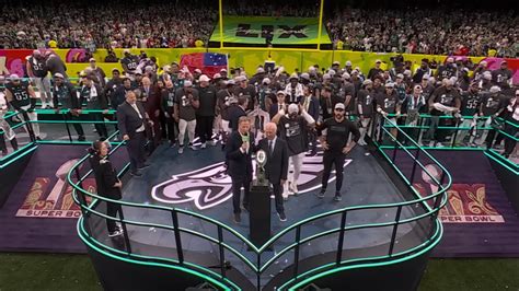 Emberek szurkolnak egy nagy kivetítő előtt Super Bowlon