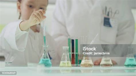 Gyerekek laboratóriumi köpenyben kémiai kísérletet végeznek