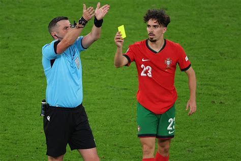 Játékvezető és egy játékos a pályán, sárga lap