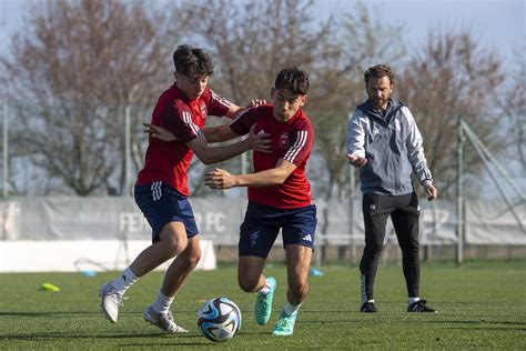Futballedző egy csapatnak tart edzést, bójákkal és labdákkal.