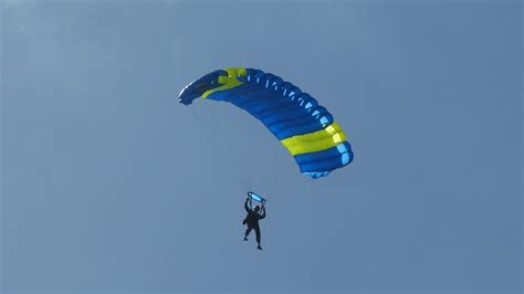 Ejtőernyős célbaugrók landolás közben, háttérben versenyszámokat jelölő pontok