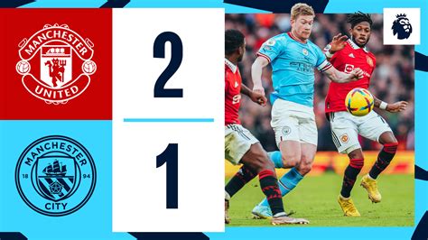Manchester United és Manchester City csapatlogók egy focipályán